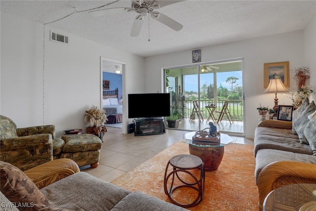 tiled living room with a textured ceiling, a fireplace, and ceiling fan