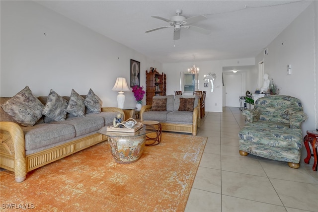 tiled living room with ceiling fan with notable chandelier