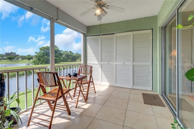 sunroom / solarium featuring a water view and ceiling fan