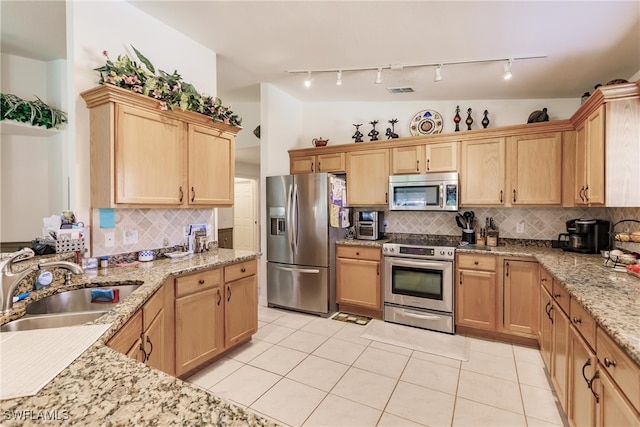 kitchen with appliances with stainless steel finishes, tasteful backsplash, sink, light tile patterned floors, and light stone countertops