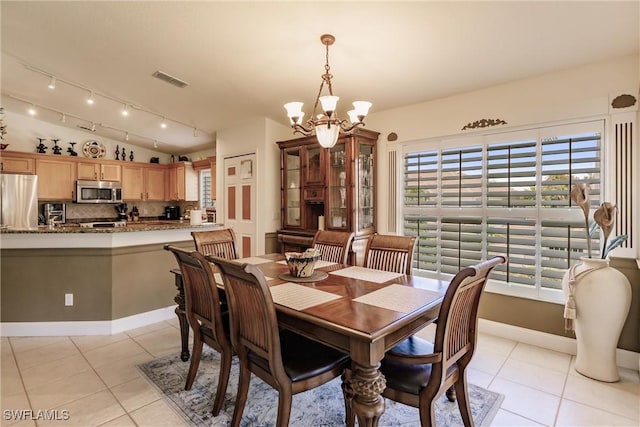 dining space featuring light tile patterned flooring, lofted ceiling, and an inviting chandelier