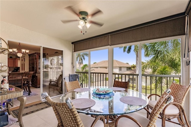 sunroom featuring ceiling fan with notable chandelier