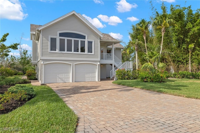 view of property featuring a garage, a front lawn, and a porch