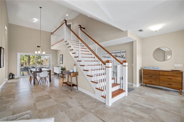 staircase with an inviting chandelier and high vaulted ceiling