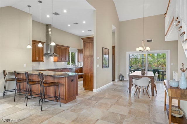 kitchen with decorative light fixtures, wall chimney exhaust hood, and high vaulted ceiling