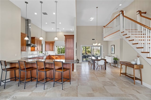 kitchen featuring pendant lighting, a notable chandelier, wall chimney exhaust hood, and kitchen peninsula