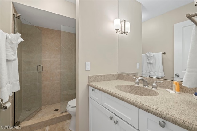 bathroom featuring tile patterned flooring, a shower with door, vanity, and toilet