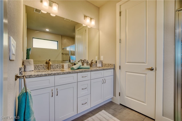 bathroom with tile patterned flooring, a shower with shower door, and vanity