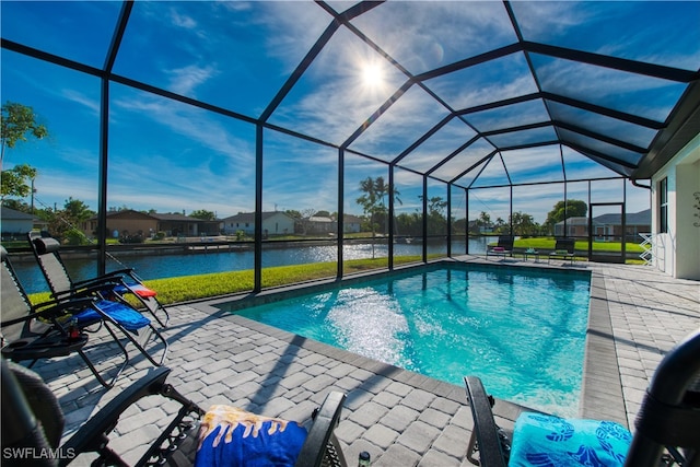 view of pool featuring a patio, a water view, and glass enclosure