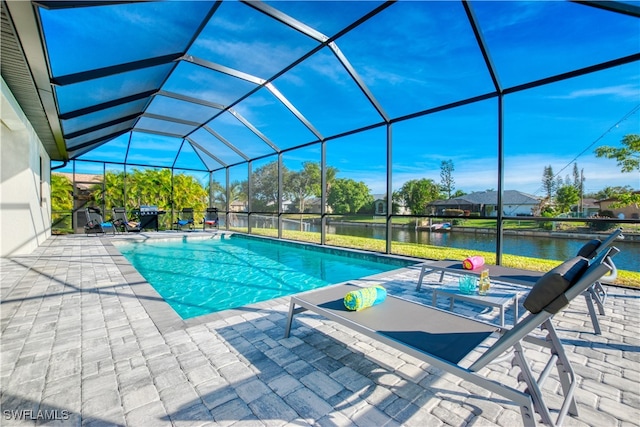 view of pool with a patio, glass enclosure, and a water view