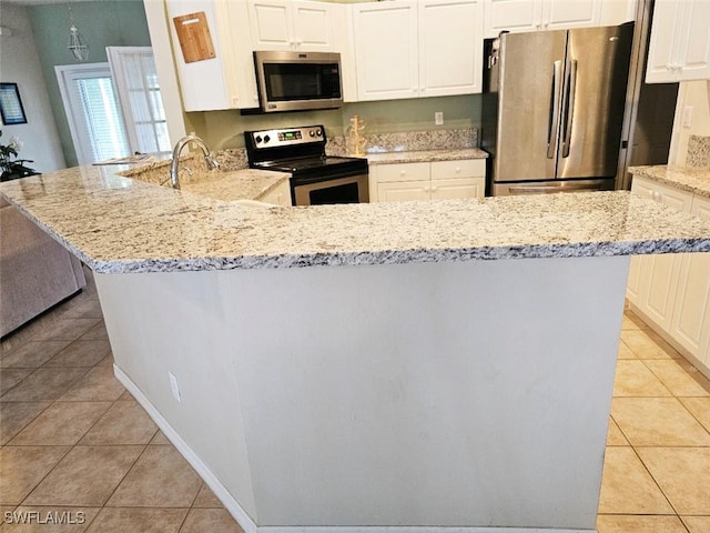 kitchen featuring light tile patterned floors, stainless steel appliances, kitchen peninsula, and light stone countertops