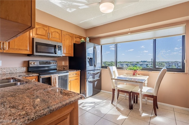 kitchen featuring a textured ceiling, light tile patterned floors, ceiling fan, and stainless steel appliances