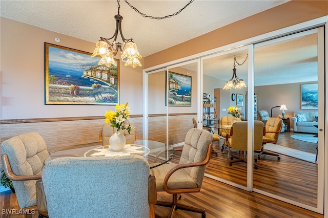 dining area with a textured ceiling, hardwood / wood-style floors, and a chandelier