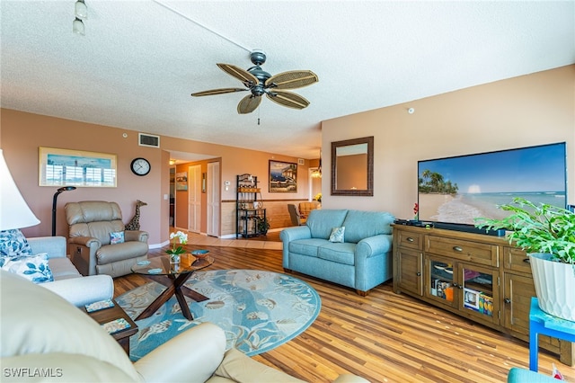 living room featuring a textured ceiling, ceiling fan, and light hardwood / wood-style flooring