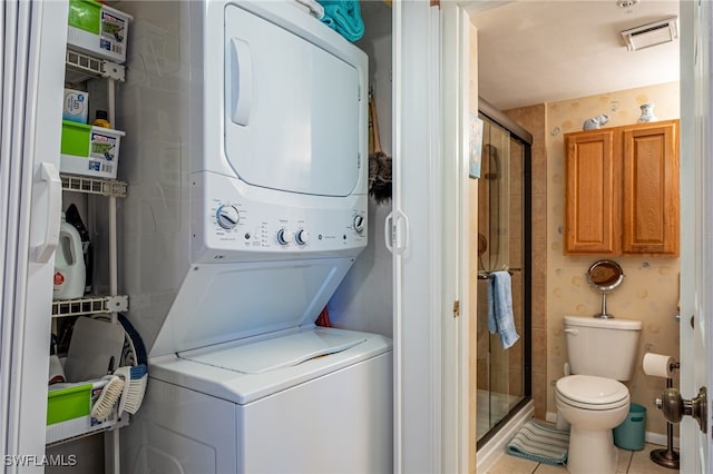 laundry room with stacked washing maching and dryer and light tile patterned floors