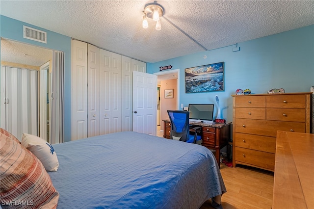 bedroom featuring light hardwood / wood-style flooring, a closet, and a textured ceiling