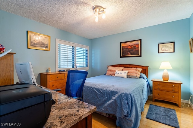 bedroom with a textured ceiling and light hardwood / wood-style floors