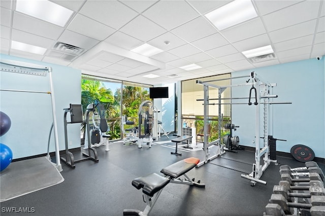 exercise room featuring a paneled ceiling and expansive windows