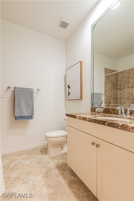 bathroom with tiled shower, vanity, and toilet