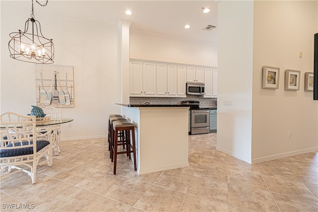 kitchen with tasteful backsplash, decorative light fixtures, white cabinetry, a kitchen breakfast bar, and appliances with stainless steel finishes