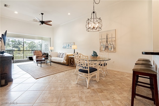 dining space with light tile patterned flooring, ceiling fan with notable chandelier, and crown molding