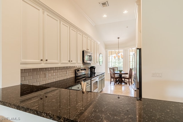 kitchen with ornamental molding, kitchen peninsula, appliances with stainless steel finishes, dark stone counters, and decorative backsplash