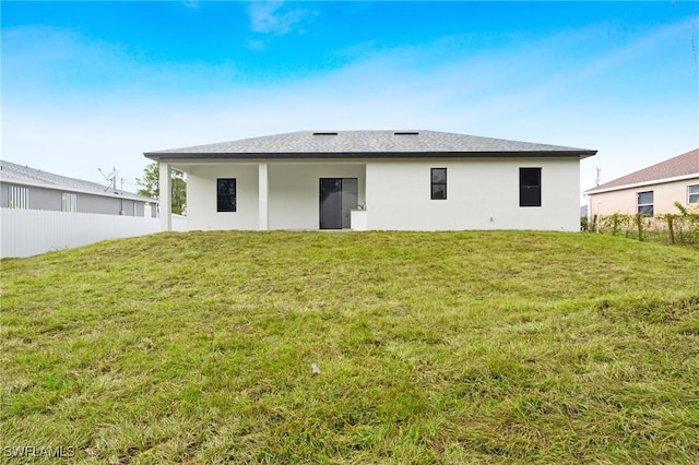 rear view of property featuring a lawn