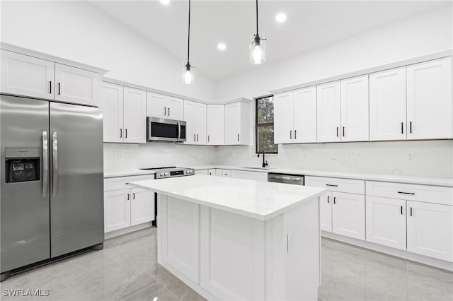 kitchen featuring white cabinets, decorative light fixtures, stainless steel appliances, and vaulted ceiling