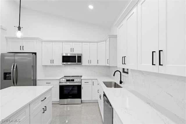 kitchen with lofted ceiling, white cabinets, sink, appliances with stainless steel finishes, and decorative light fixtures