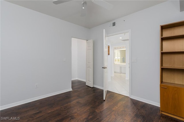 unfurnished bedroom featuring dark wood-type flooring, baseboards, a ceiling fan, and visible vents