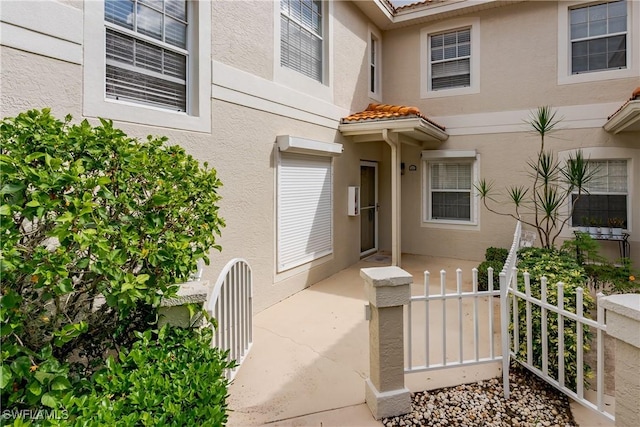 entrance to property featuring stucco siding and a tiled roof