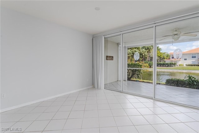 spare room with floor to ceiling windows, baseboards, a ceiling fan, and a water view