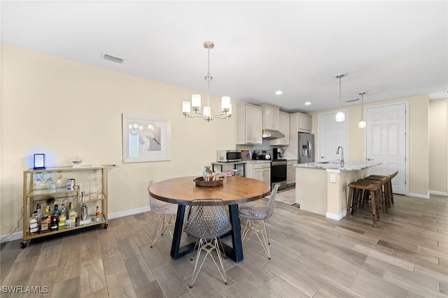 dining space with sink and a notable chandelier