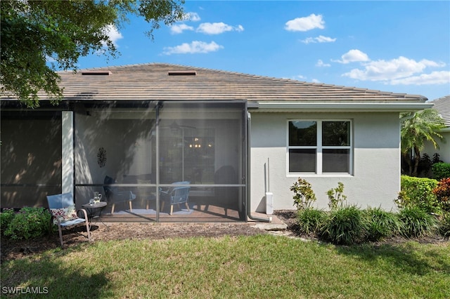 back of house featuring a sunroom, a patio area, and a lawn