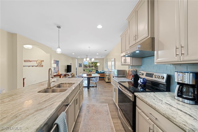 kitchen with tasteful backsplash, light stone counters, stainless steel range with electric stovetop, sink, and pendant lighting