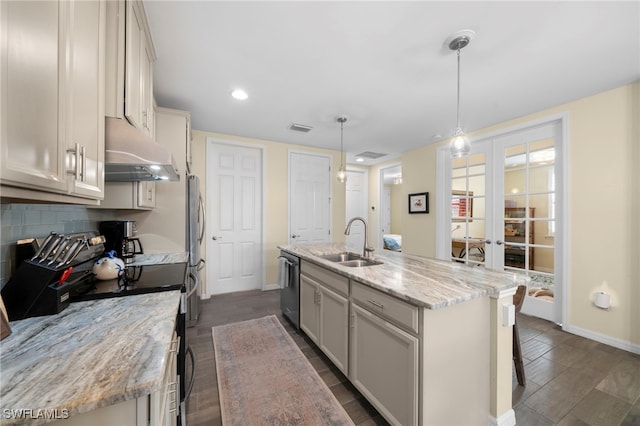 kitchen featuring sink, french doors, stainless steel appliances, pendant lighting, and a kitchen island with sink