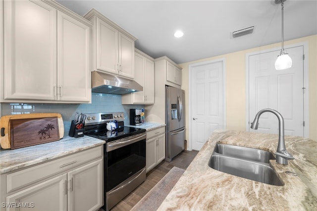 kitchen featuring sink, decorative backsplash, light stone countertops, decorative light fixtures, and stainless steel appliances