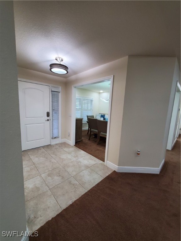 entrance foyer featuring a textured ceiling and light colored carpet