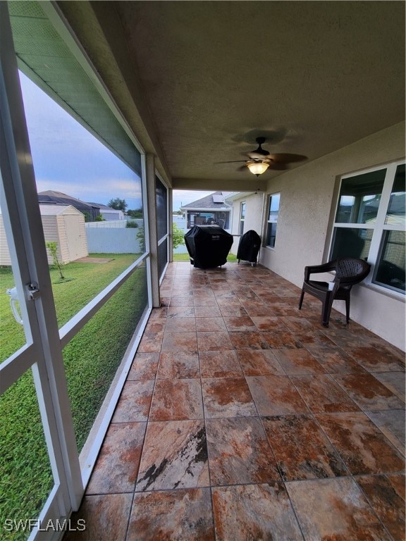 unfurnished sunroom with ceiling fan