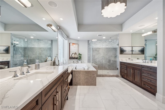 bathroom with a raised ceiling, vanity, and separate shower and tub