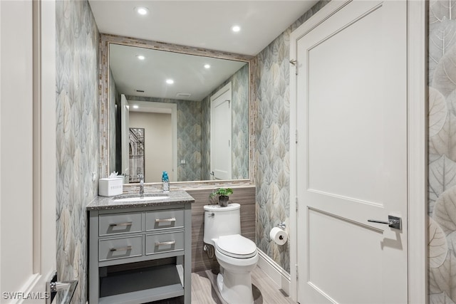 bathroom featuring tile walls, hardwood / wood-style flooring, vanity, and toilet