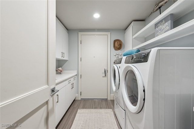 washroom featuring wood-type flooring, cabinets, and washing machine and dryer