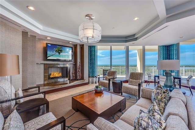 living room featuring a premium fireplace, a raised ceiling, and expansive windows