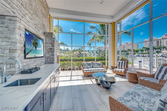 exterior space featuring light wood-type flooring, light stone counters, and sink