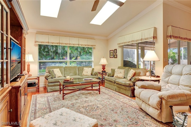 living room with lofted ceiling with skylight, ornamental molding, hardwood / wood-style floors, and ceiling fan