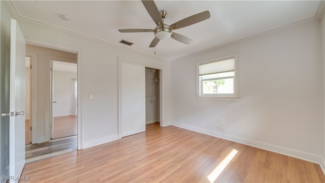 unfurnished bedroom with light wood-type flooring, crown molding, ceiling fan, and a closet