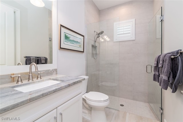 bathroom featuring tile patterned flooring, a shower with door, vanity, and toilet