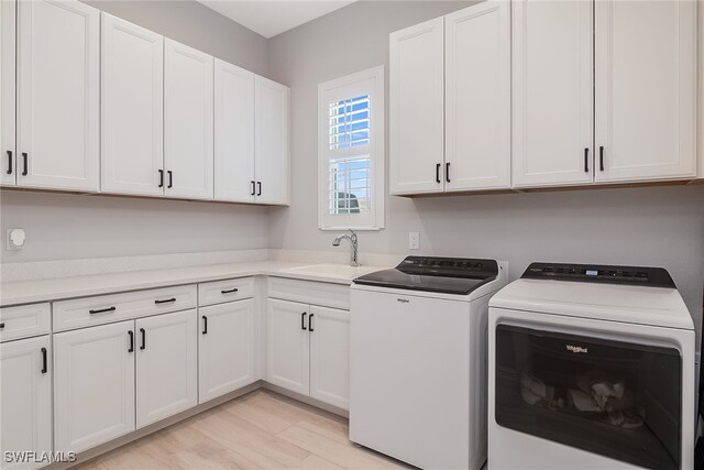 washroom with light hardwood / wood-style floors, sink, independent washer and dryer, and cabinets