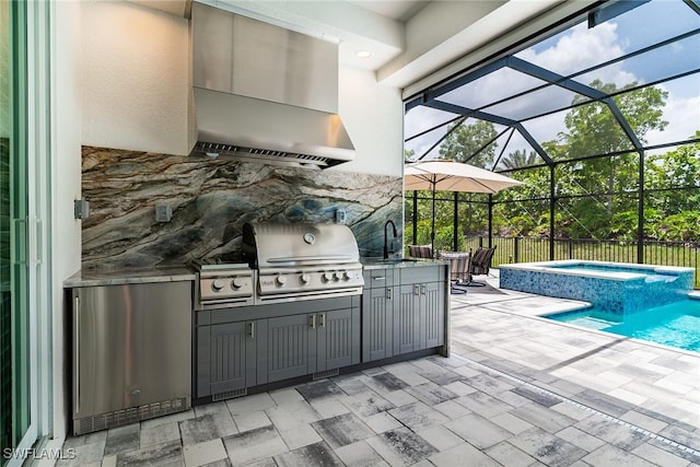 exterior space featuring glass enclosure, an in ground hot tub, a grill, a patio area, and sink