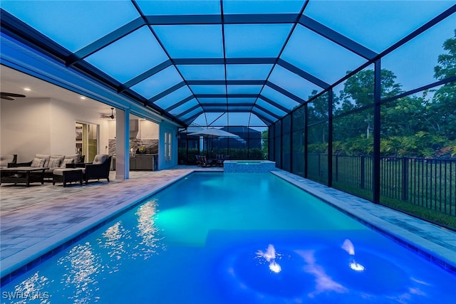 view of pool featuring glass enclosure, outdoor lounge area, ceiling fan, and a patio